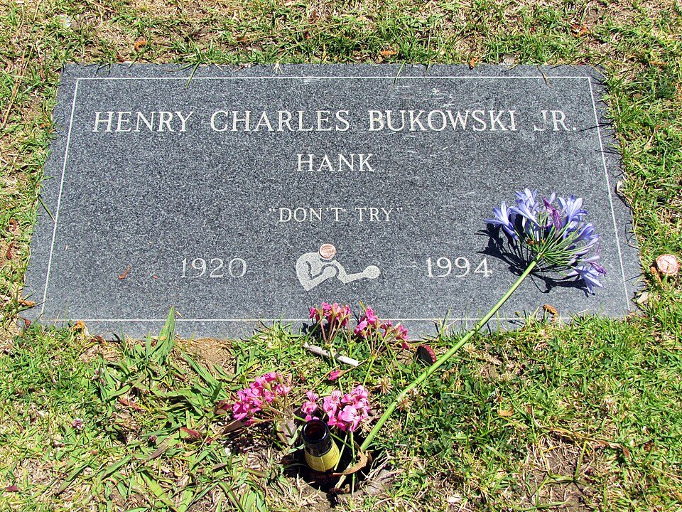Flat granite gravestone reading Henry Charles Bukowski Jr, Hank, Don’t Try, 1920–1994, with flowers